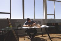 Vista frontal do arquiteto masculino asiático trabalhando no modelo arquitetônico na mesa em um escritório moderno — Fotografia de Stock