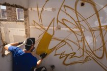 Вид сзади на выветренную стену молодой кавказской граффити-художницы — стоковое фото