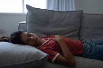 Vista laterale di bella donna di razza mista che dorme sul divano a casa — Foto stock