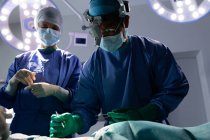 Vista a basso angolo dei chirurghi che eseguono operazioni in sala operatoria in ospedale — Foto stock