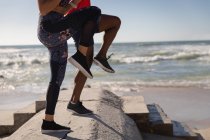 Baixa seção de casal fazendo jogging local na praia — Fotografia de Stock