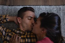 Visão de alto ângulo de casal multi-étnico se beijando enquanto deitado no sofá em casa — Fotografia de Stock