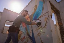 Низкий угол обзора молодых кавказских граффити художник распылитель живописи на выветренной комнате стены — стоковое фото
