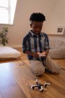 Vue de face de petit garçon afro-américain mignon jouant avec drone sur la table à la maison — Photo de stock