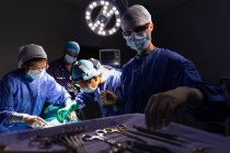 Side view of surgeons concentrated performing operation in operating room at hospital — Stock Photo
