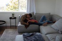 Seitenansicht von jungen multiethnischen Paaren, die sich küssen, während sie zu Hause auf dem Sofa liegen — Stockfoto