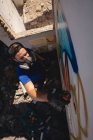 Высокий угол обзора молодых кавказских граффити художник распылитель живописи выветренной стеной комнате — стоковое фото