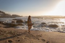Вид сбоку на женщину, гуляющую на пляже в солнечный день — стоковое фото