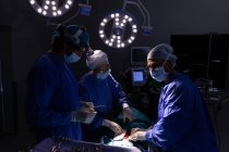 Vista frontal de cirujanos concentrados realizando operación en quirófano en el hospital - foto de stock