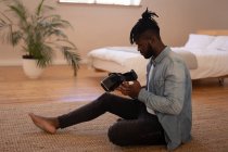 Side view of handsome African-American man using virtual reality headset at home — Stock Photo