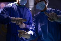Mittelteil der Chirurgen im Gespräch während der Operation im Operationssaal des Krankenhauses — Stockfoto
