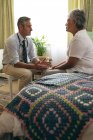 Vue latérale du médecin masculin caucasien interagissant avec une patiente âgée de race mixte à la maison de retraite — Photo de stock