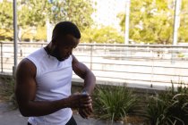 Вид збоку молодих афро-американських fit чоловік дивиться на смарт-дивитися на вулиці — стокове фото