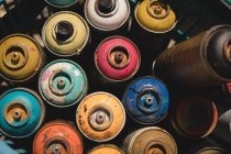 Vista de ángulo alto de latas de aerosol de colores guardados en la cesta - foto de stock