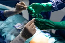 Close-up de cirurgiões segurando faca cirúrgica e fórceps na sala de cirurgia durante a cirurgia no hospital — Fotografia de Stock