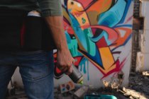 Visão traseira do jovem artista de grafite caucasiano de pé com pintura em spray no beco — Fotografia de Stock