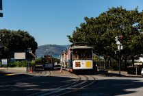 Tram moving on a track across the town street on a sunny day — Stock Photo