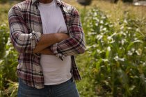Mid section of male farmer standing with arm crossed in the field at farm — Stock Photo