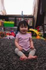 Retrato de un pequeño bebé asiático lindo mirando a la cámara y sentado en la alfombra en casa - foto de stock