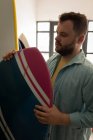 Vue de face de l'homme caucasien concentré vérifiant la planche de surf dans un atelier — Photo de stock