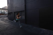 Vista lateral do ajuste jovem mista corrida mulher correndo na rua na cidade — Fotografia de Stock