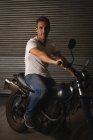 Portrait of Caucasian male bike mechanic driving bike in garage — Stock Photo