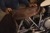 Mittelteil des männlichen Fahrradmechanikers repariert neuen Sitz im Motorrad in der Garage — Stockfoto
