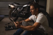 Вид збоку Кавказького чоловічого велосипеда механік з використанням цифрової таблетки в гаражі — стокове фото