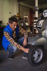 Vue de face du mécanicien de vélo caucasien réparer vélo de roue dans le garage — Photo de stock