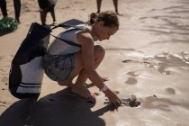 Вид сбоку молодой кавказки-волонтера, убирающей пляж в солнечный день — стоковое фото