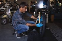Vista lateral de la bicicleta caucásica mecánica reparación de bicicletas con guantes en el garaje - foto de stock