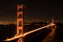Vista frontale del ponte di notte con luci e città sullo sfondo — Foto stock