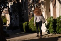 Вид ззаду жінки, що йде на вулицю в сонячний день — стокове фото