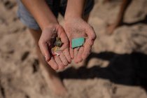 Close-up de voluntário segurando resíduos na mão na praia em um dia ensolarado — Fotografia de Stock