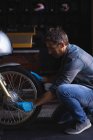 Side view of Caucasian bike mechanic using ratchet wrench to adjust bike tire — Stock Photo