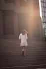 Заднього виду азіатській жінці, що йде вгору по сходах в сонячний день — стокове фото