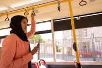Side view of a beautiful mixed-race woman waiting for the stop while standing in bus — Stock Photo