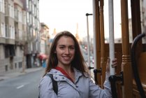 Vorderansicht einer glücklichen jungen Kaukasierin, die außerhalb des fahrenden Fahrzeugs in der Stadt hängt — Stockfoto