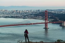 Rückansicht einer Frau beim Fotografieren einer Brücke an einem sonnigen Tag — Stockfoto
