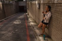Vista laterale della giovane donna di razza mista che ascolta musica sulle cuffie per strada — Foto stock