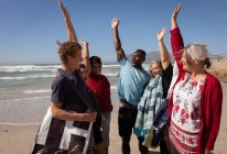 Vista frontale del gruppo multietnico di volontari che formano pila di mano sulla spiaggia — Foto stock