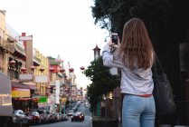 Visão traseira da mulher capturando foto da cidade — Fotografia de Stock