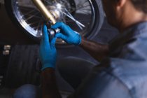 Hochwinkelaufnahme eines kaukasischen Fahrradmechanikers, der mit Ratschenschlüssel in der Garage arbeitet — Stockfoto