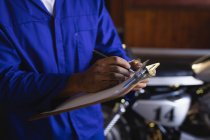 Середня секція велосипедного механіка підтримка автомобільних записів на кишені в гаражі — стокове фото