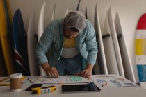 Vorderseite des kaukasischen Mannes zeichnet Surfbrett-Skizze in einem Workshop — Stockfoto