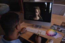 Вид ззаду чоловічий графічний дизайнер змішаної раси з використанням графічного планшета для розробки моделі жінки на екрані в сучасному офісі — стокове фото