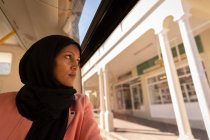 Вид спереду вдумлива змішана жінка, яка дивиться за межами автобуса під час подорожі на автобусному вокзалі — стокове фото
