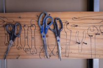 Три ножницы висят на гвоздях в мастерской — стоковое фото