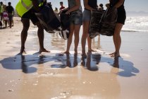 Baixa seção de grupo de voluntários limpeza praia em um dia ensolarado — Fotografia de Stock