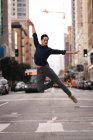 Vista frontal del joven asiático guapo saltando y bailando en la calle - foto de stock